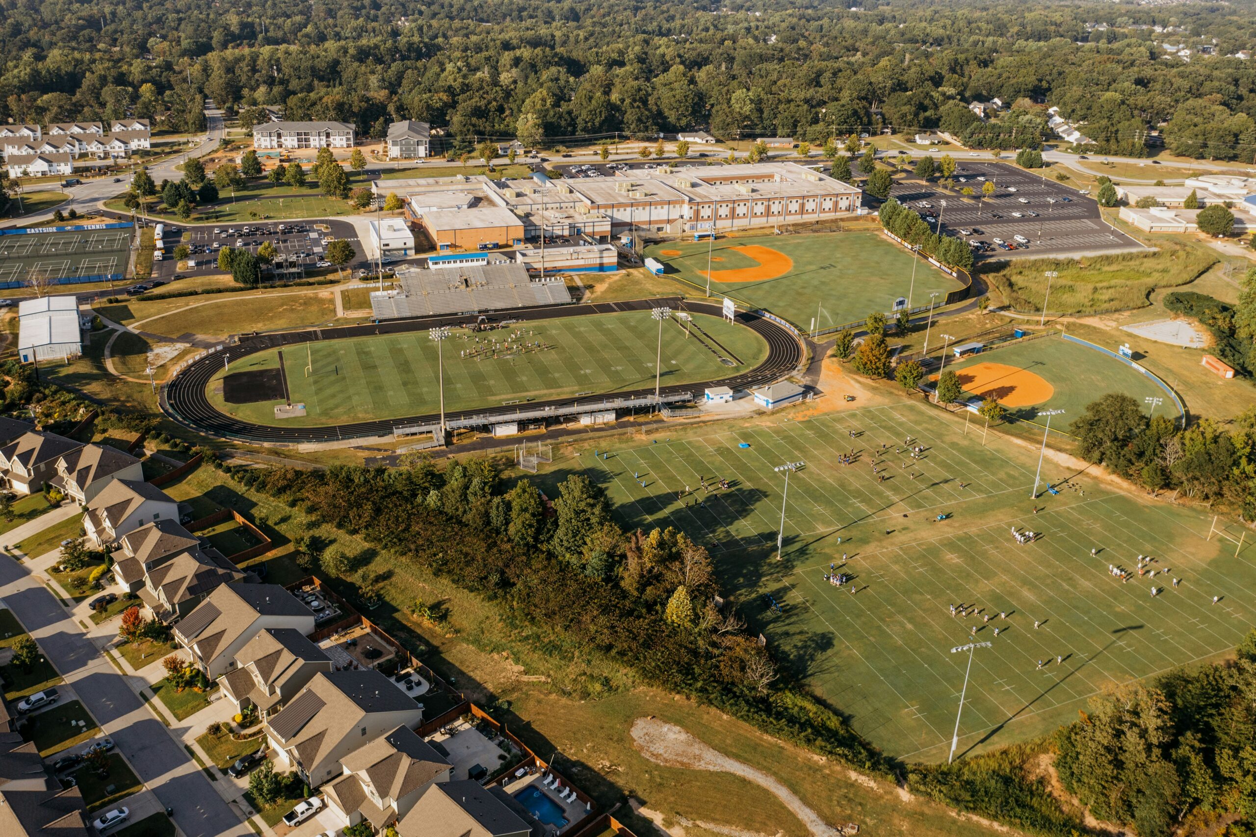 Aerial view of a school campus showing buildings, sports fields and running track within the site boundary