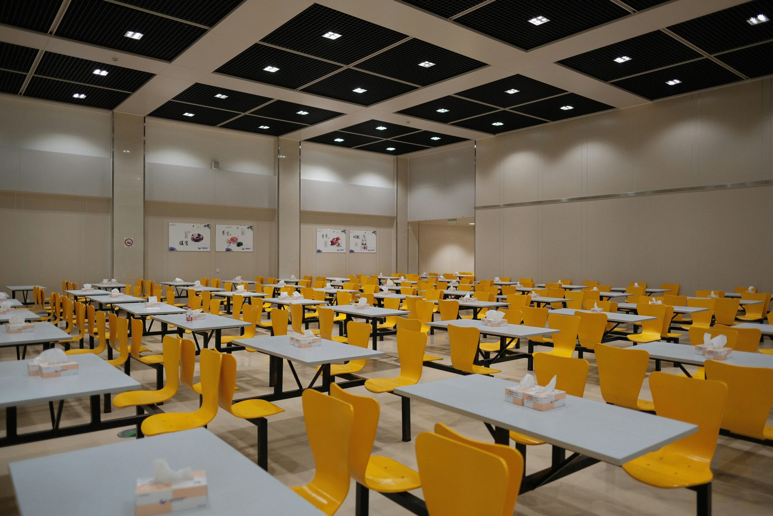 School dining hall with rows of tables and bench seating showing furniture layout and circulation space