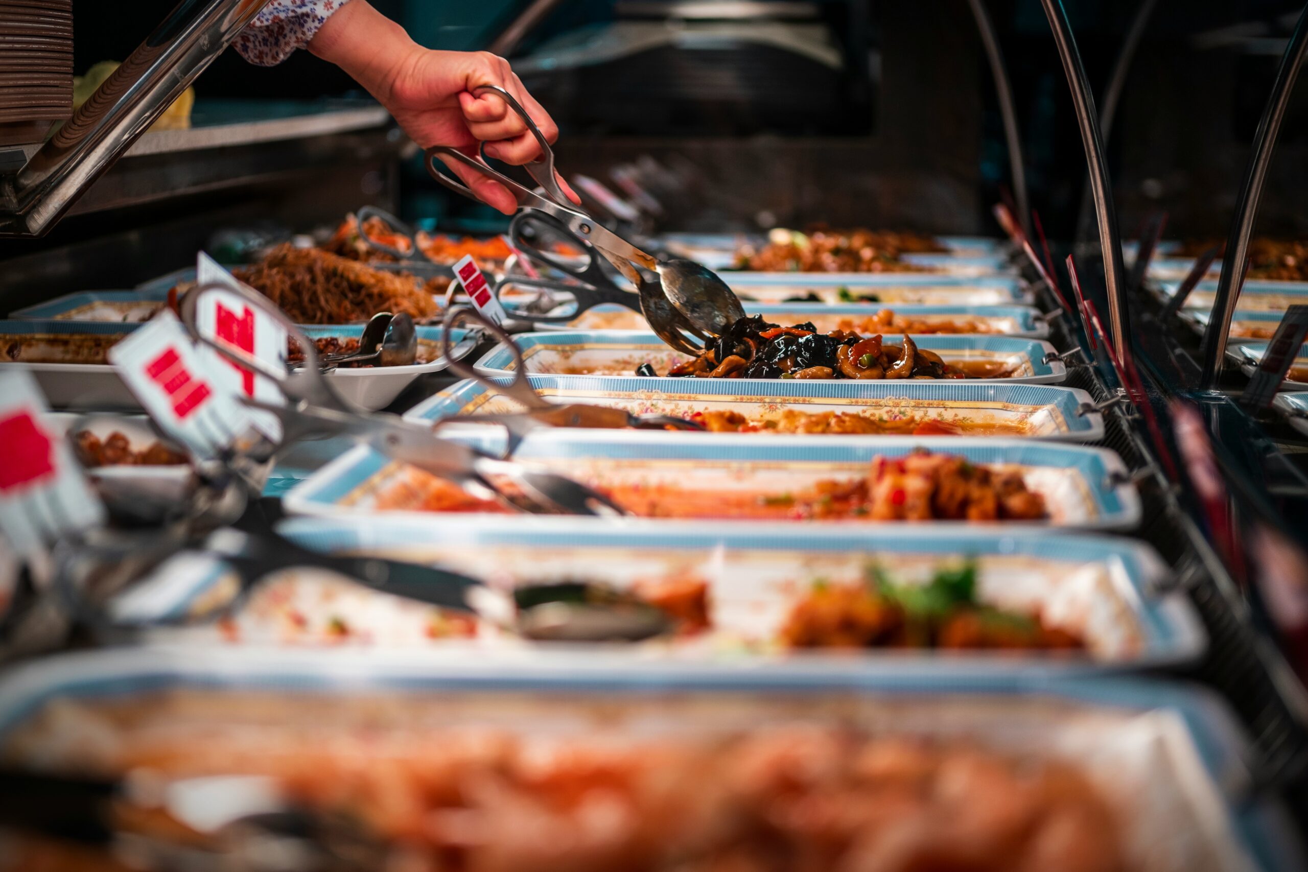 School canteen servery counter with a hot food service line and trays at a school dining hall
